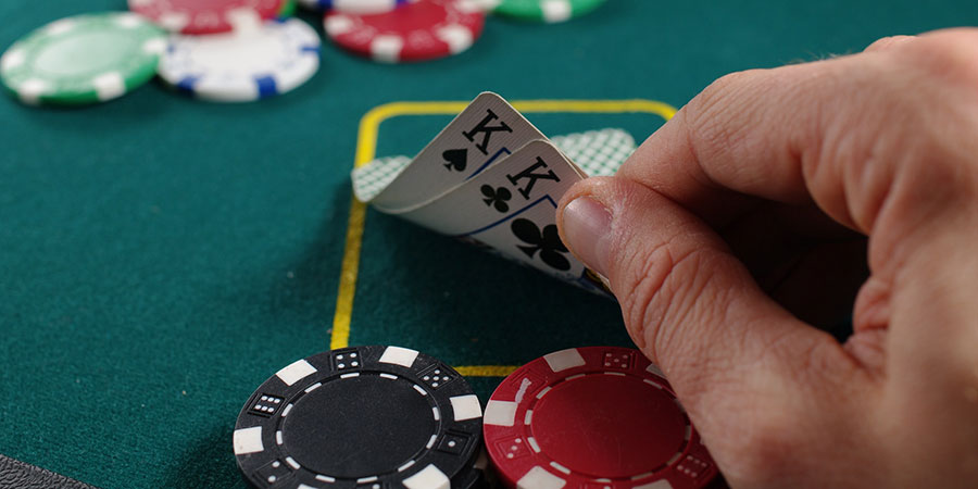 a person playing cards on a table, close up view of his cards and casino chips